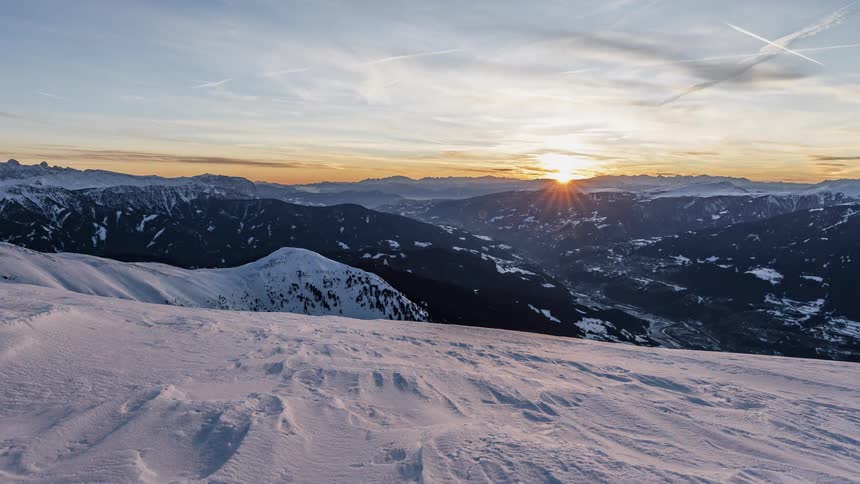 Clouds float over snowy mountains at sunset
