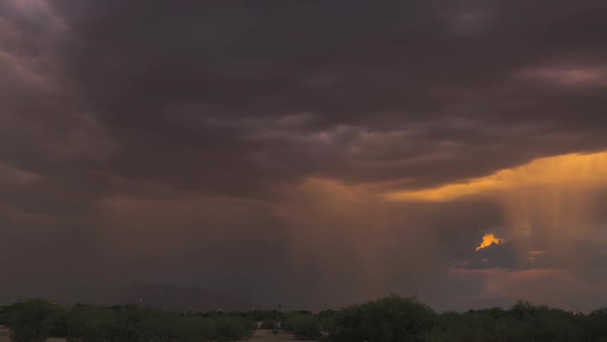 A rain storm hovers over a large plain