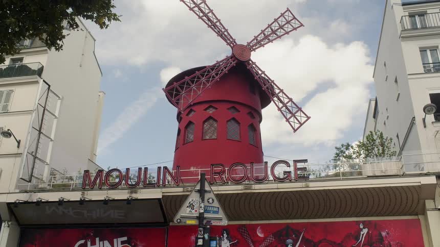 Windmill sits on top of the moulin rouge on a sunny day