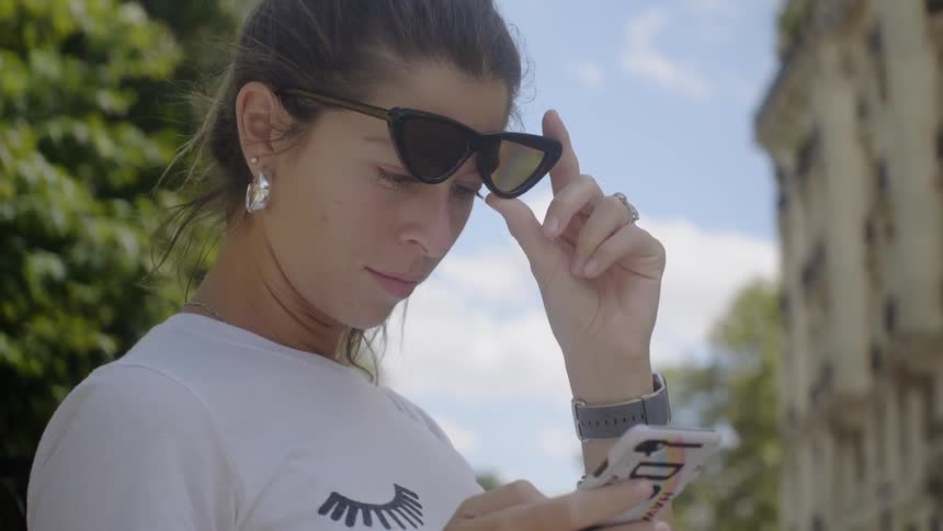 A woman looks at her phone outside