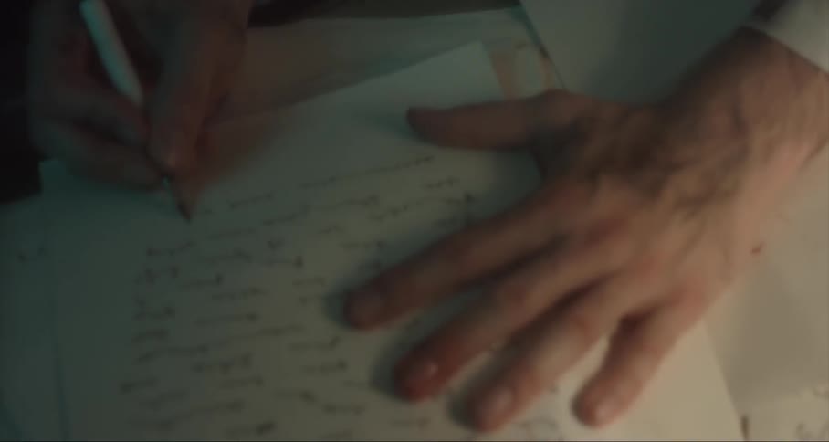 A man writes on paper with a pencil