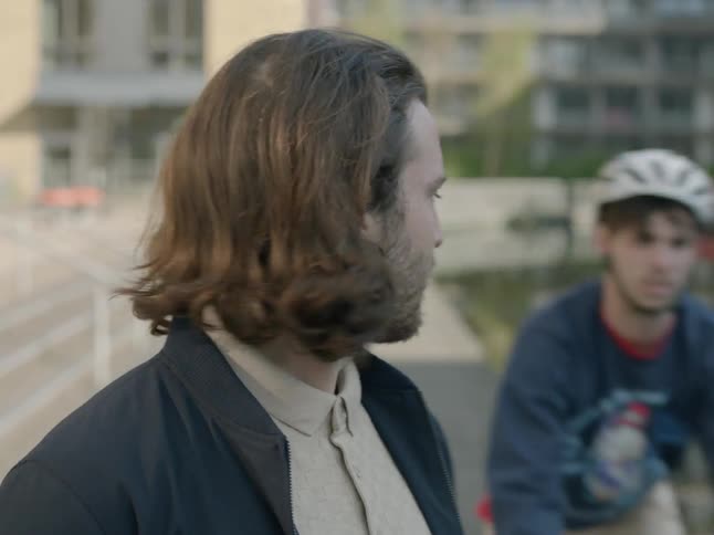 A bicyclist passes by a man