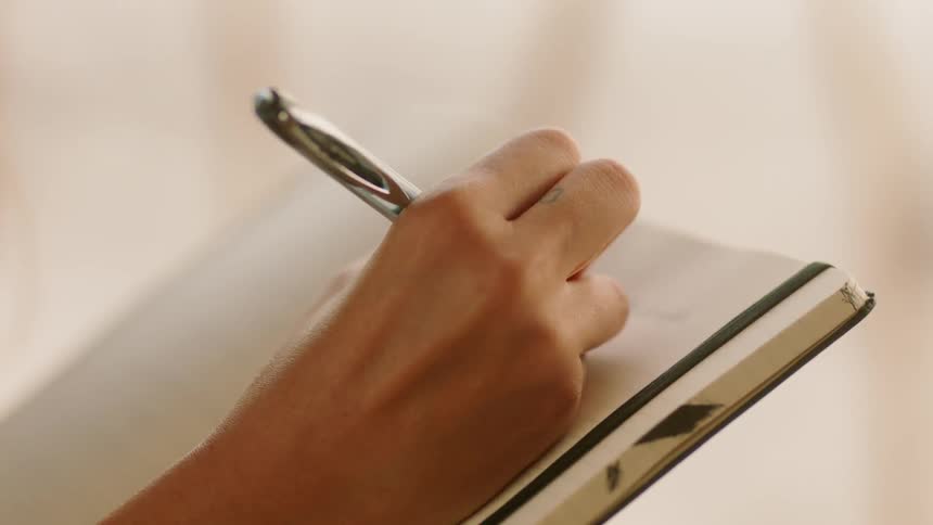 Person uses a pen to write on a white book