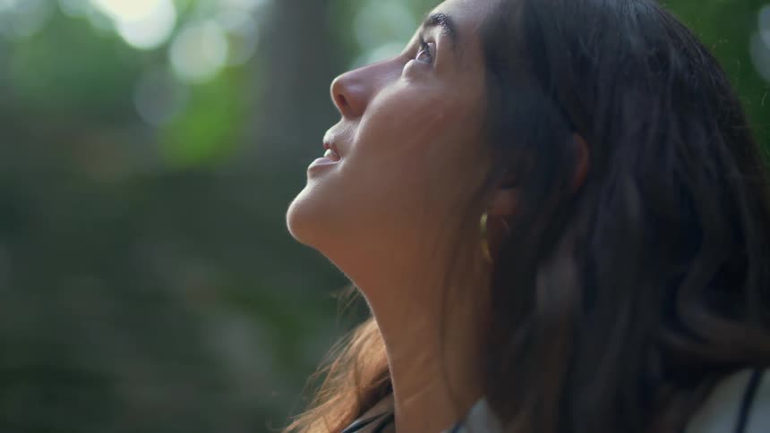A woman looks upward outside on a sunny day