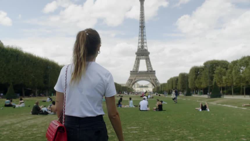 A woman walks towards the eiffel tower