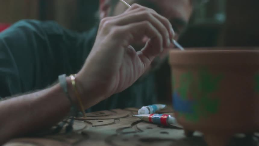 A man and woman paint clay pots