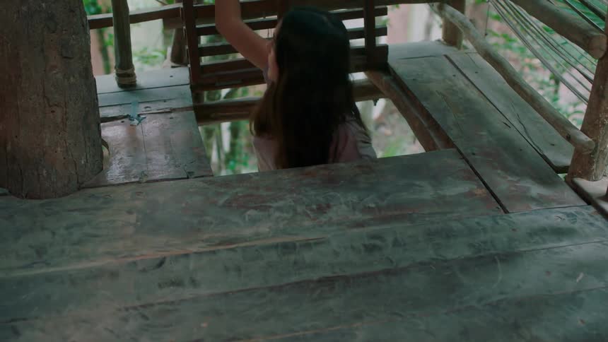 A woman enters a tree house through the floor