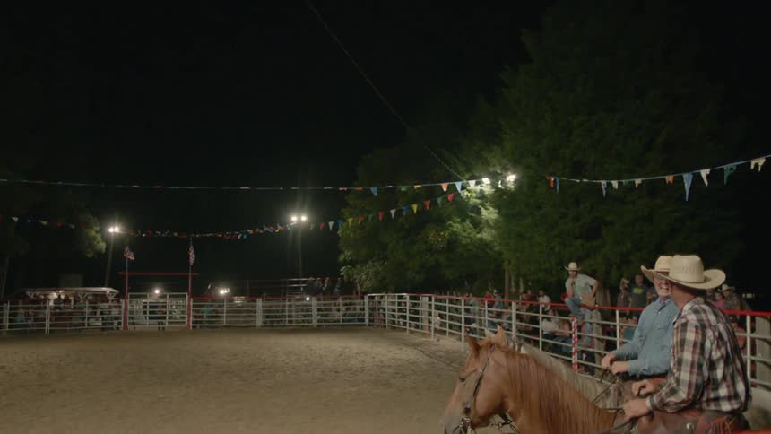Two men talk while riding horses
