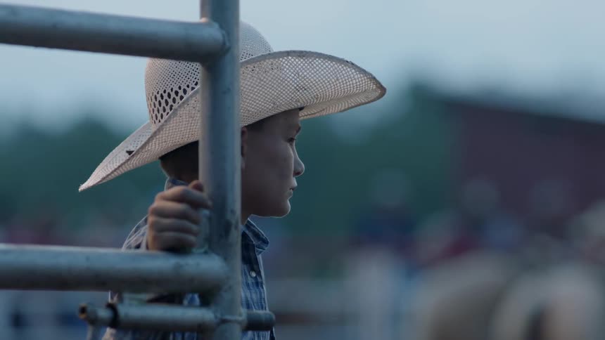 A young boy leans on a steel gate