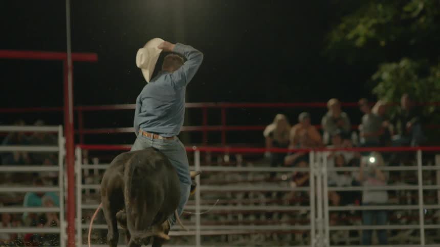 A cowboy rides a bull in an arena