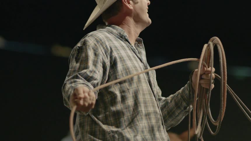 A cowboy rolls up a rope lasso