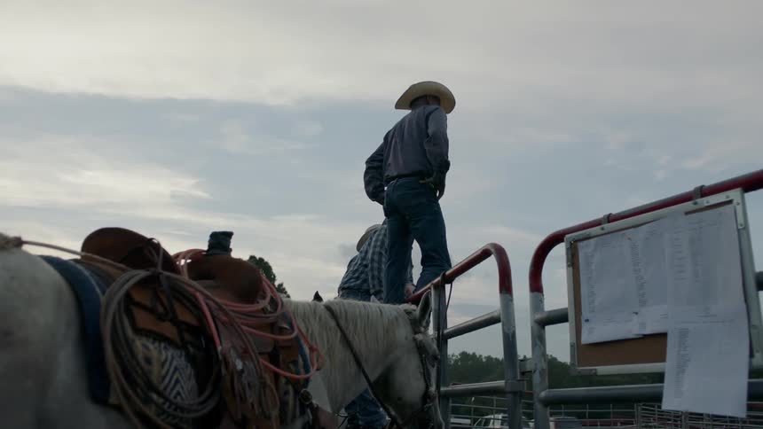 Cowboys lean and stand on steel gates