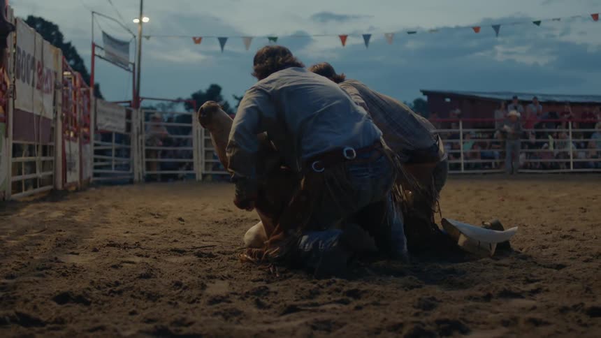 Two men grab a bull and try to hold it still