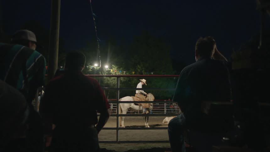 Man gets off of a horse in a corral