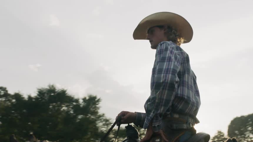 A cowboy rides a horse at sunset