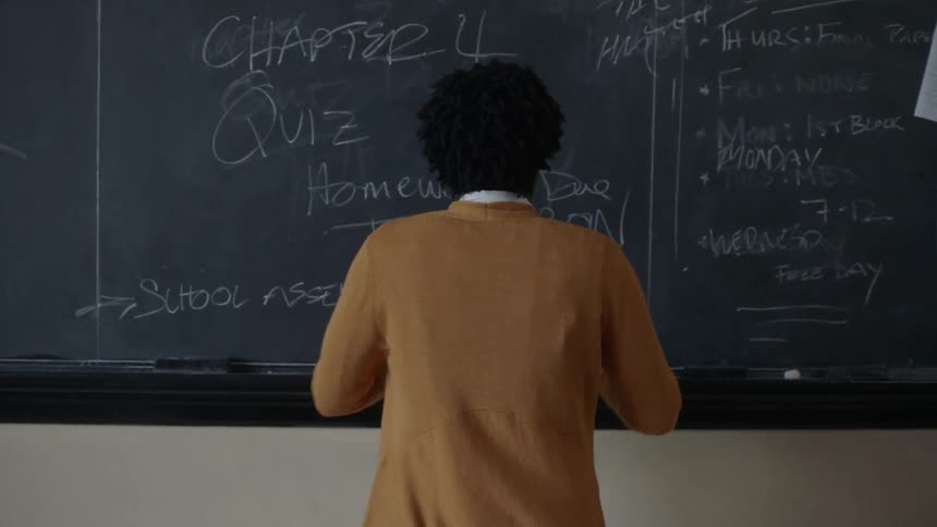 A teacher stands up and approaches the black board