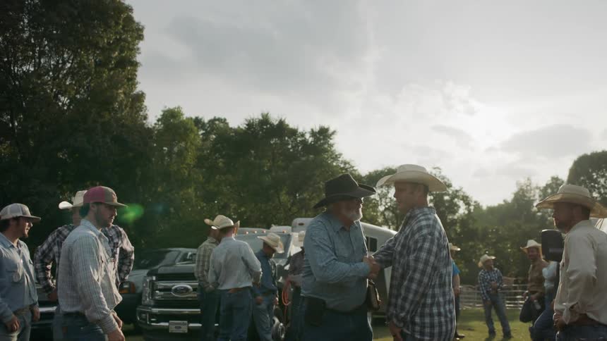 Two cowboys greet each other at a gathering