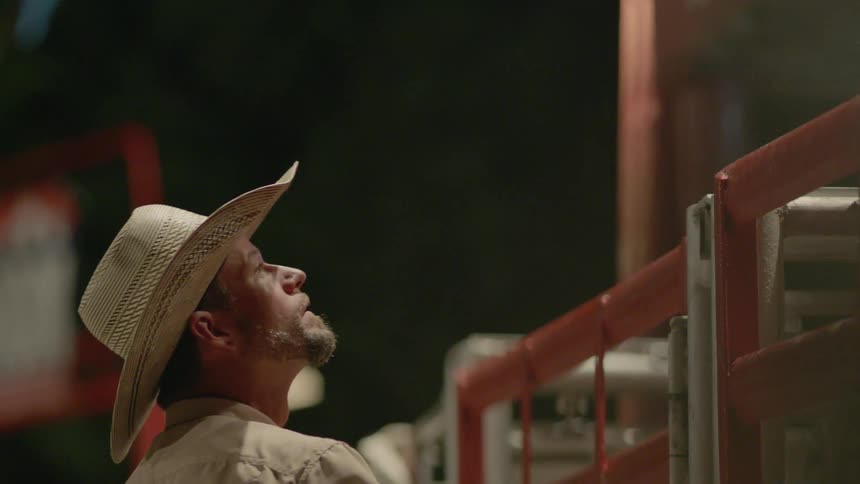 A man looks up over the fence in the rodeo