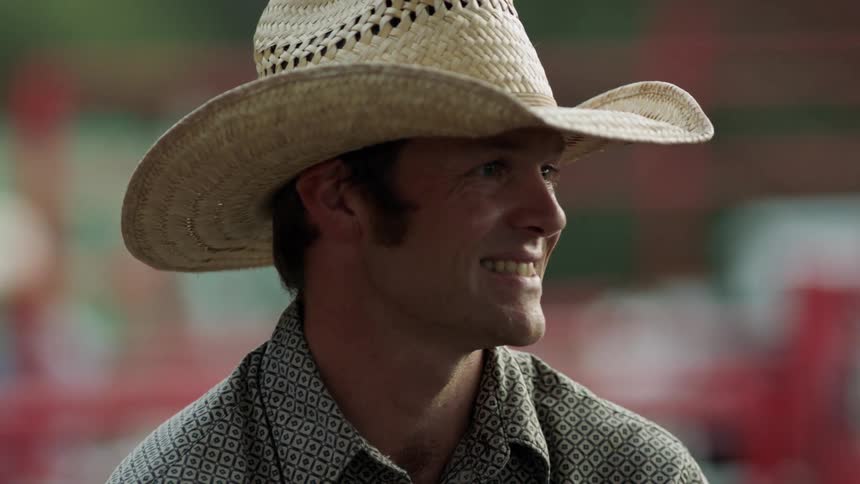 A man wearing a cowboy hat smiles