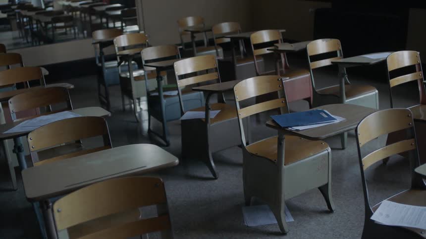 Empty desks sit in a classroom
