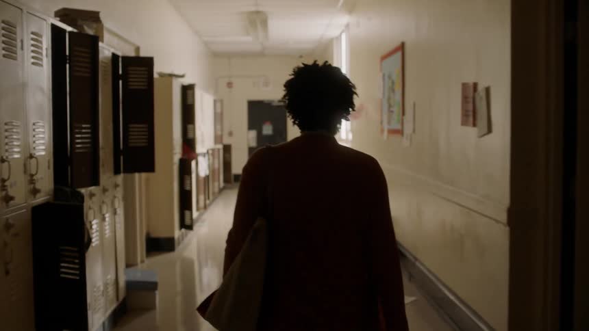 A teacher walks down a school hallway