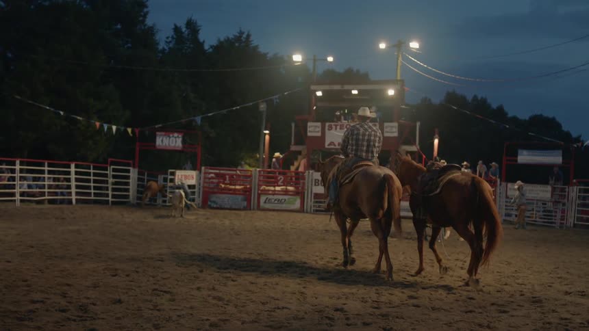 A cowboy rides a horse in a rodeo arena