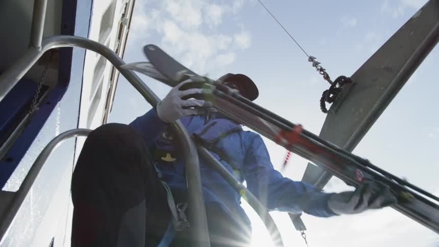 Man grabs skis that are being handed out a window