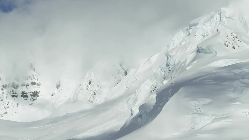 Clouds float above a snowy mountains