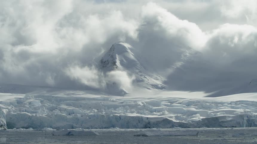 Clouds float over snowy mountains