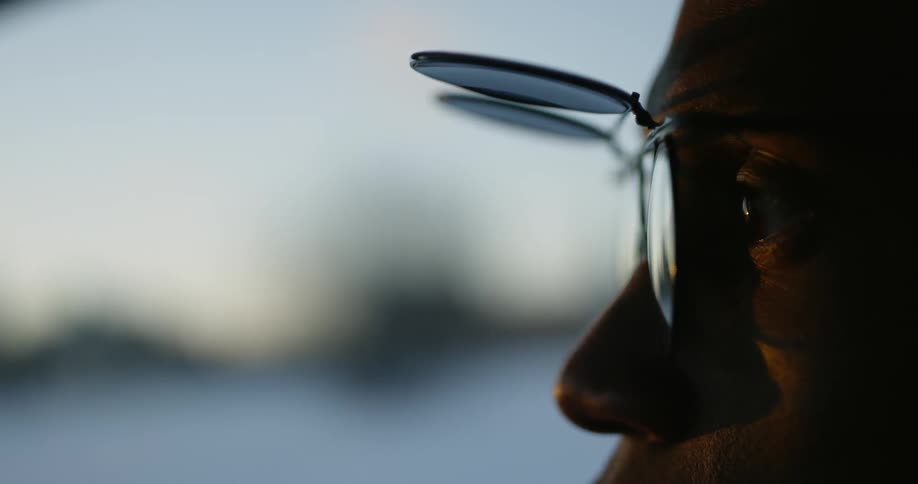Man stares ahead as he wears flip sunglasses