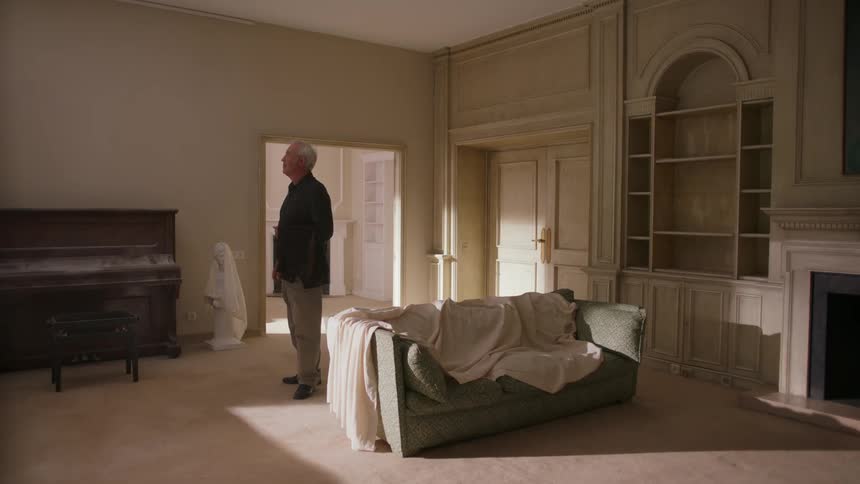 Man holds a jacket over his arm as he walks around a room