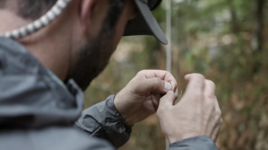 A man ties a hook onto a fishing line