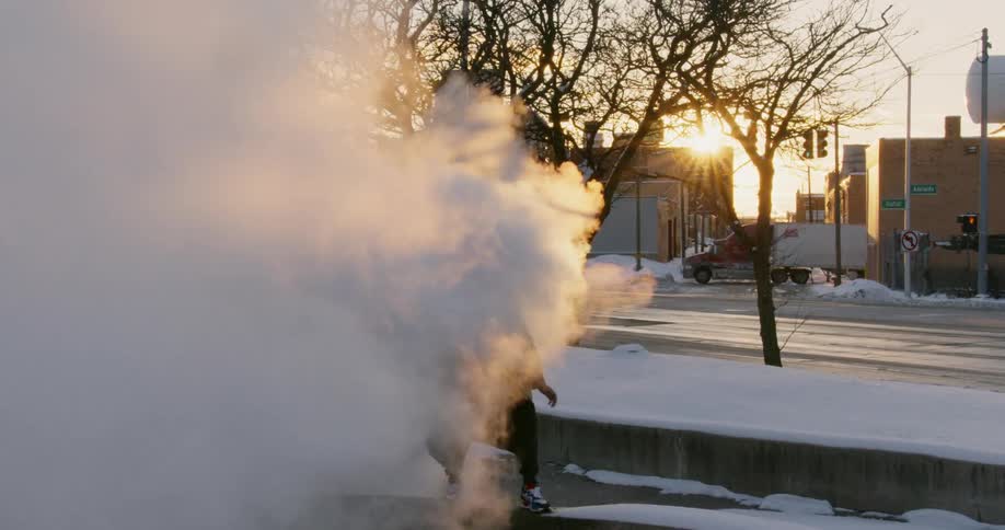 A man is dancing outside in a cloud of steam on a winter morning