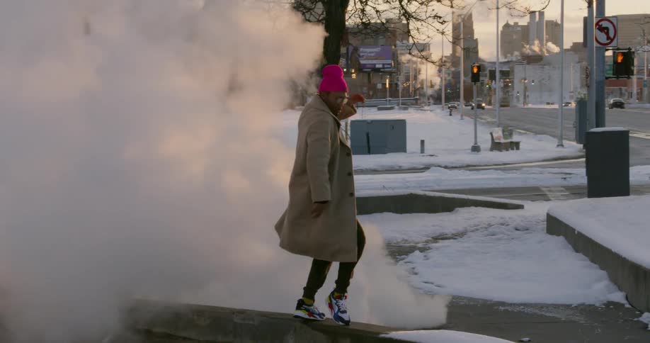 A man dances in steam by the street