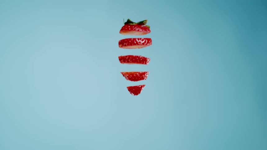 Slices of a cut strawberry descending slowly in the order of the cuts