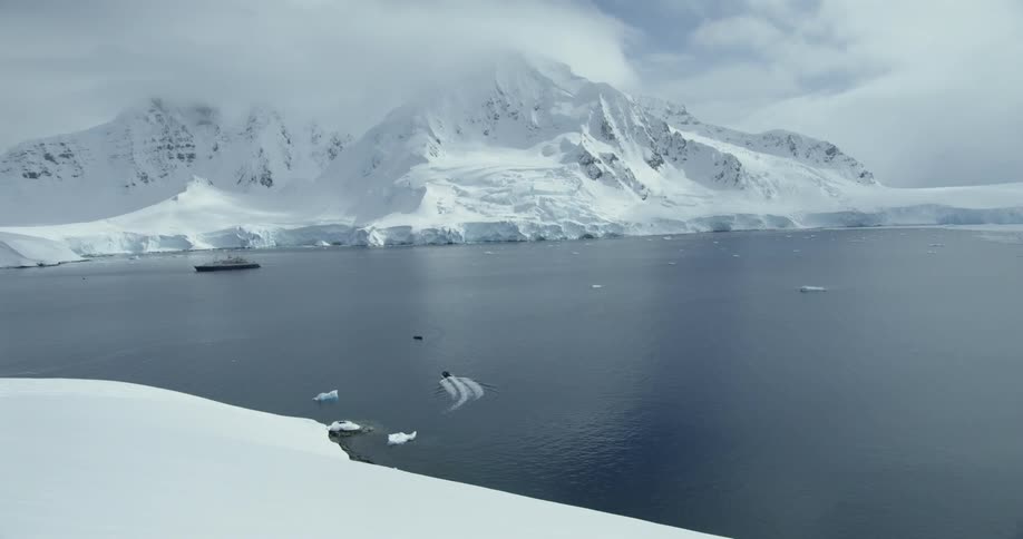 A ship is anchored off a snowy coast