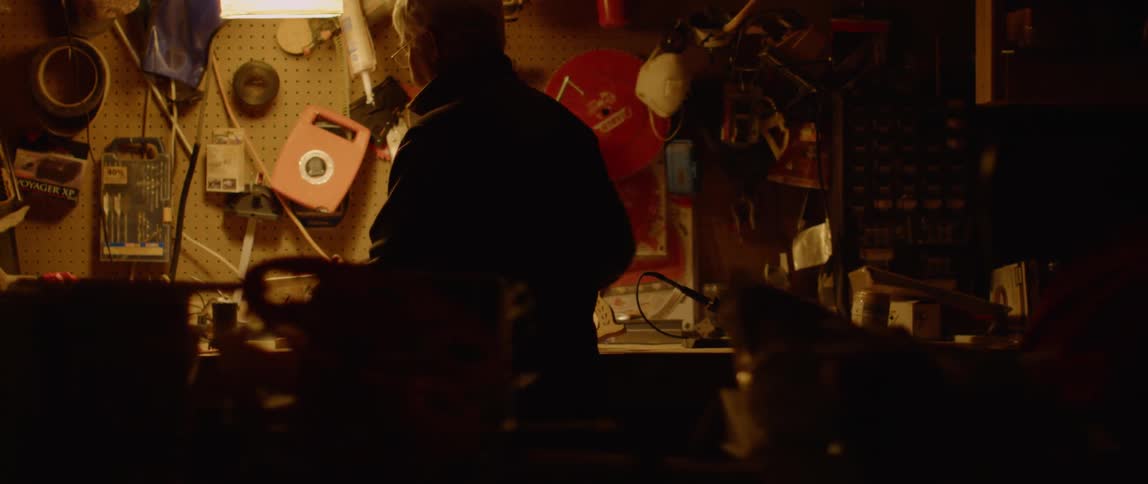 Man sits at a workbench as he hammers