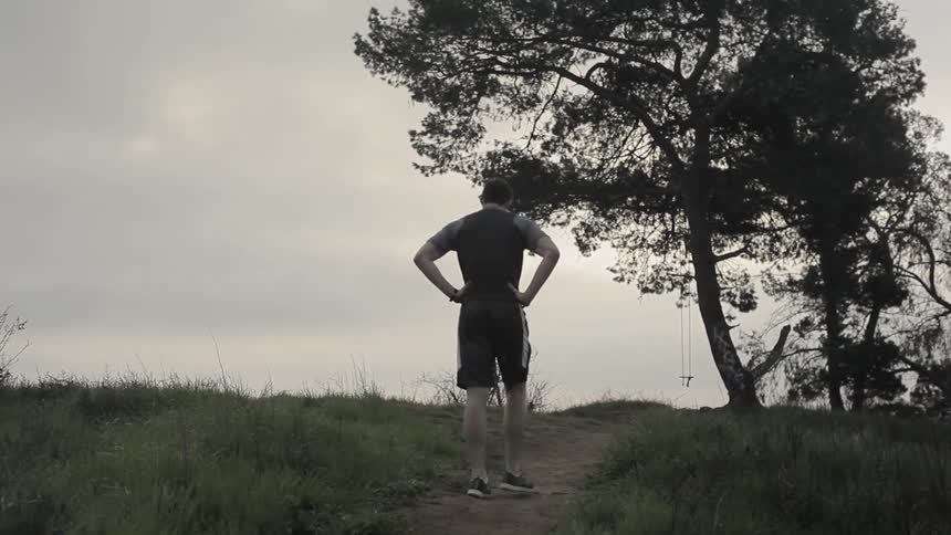 A man jogs up a hill on an overcast day