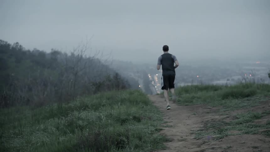 A man jogs over hills in a rural area