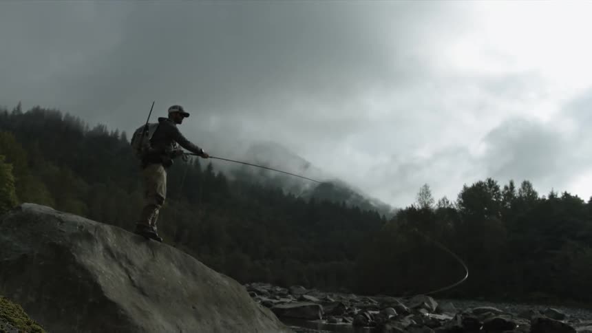 A fisherman stands on a boulder