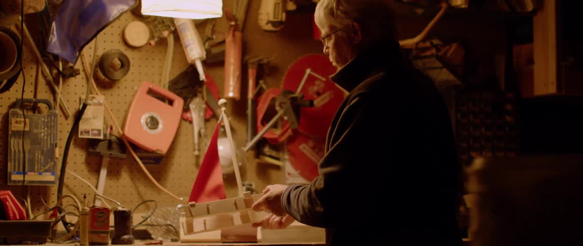 A man works on a wooden boat in a workshop