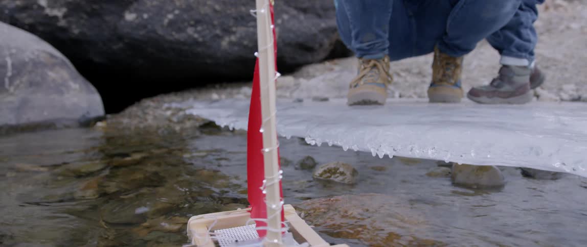 Small homemade boat launching from an icy shore by a man and a child