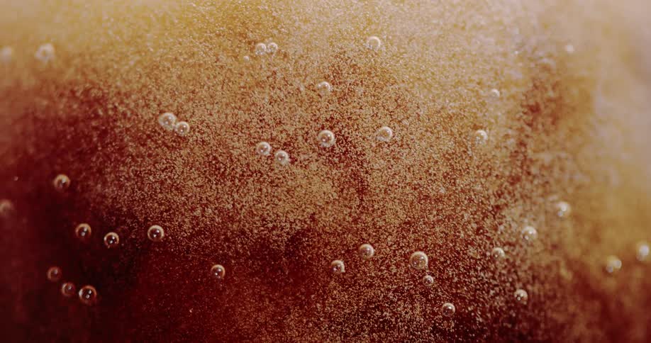 Carbonated soda bubbles form in a glass