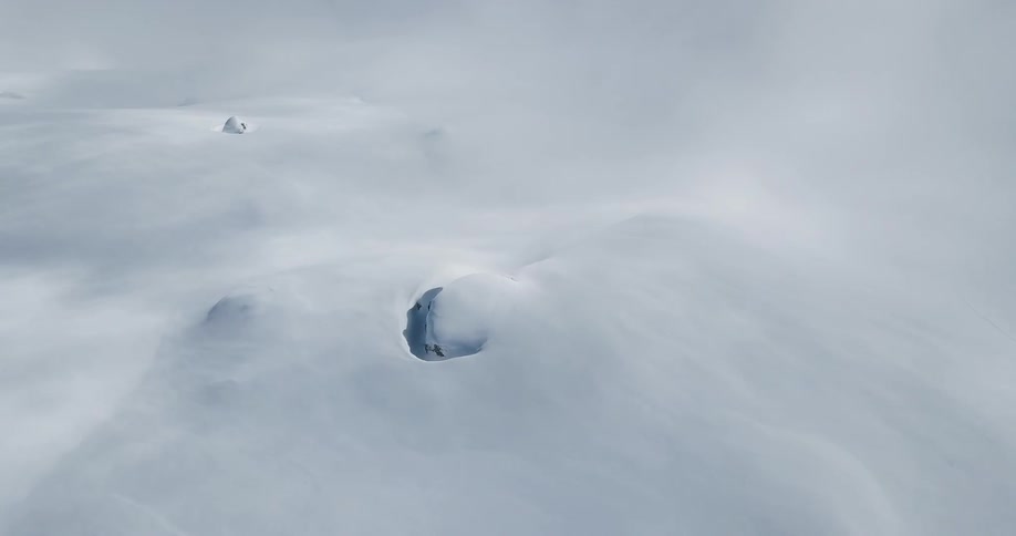 Clouds float over a snowy mountain