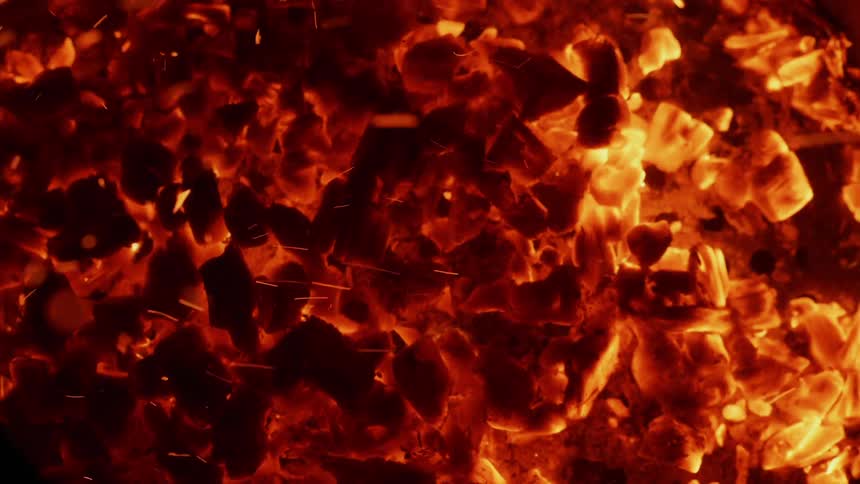 Sparks and ash swirl as fire is burning up some organic matter
