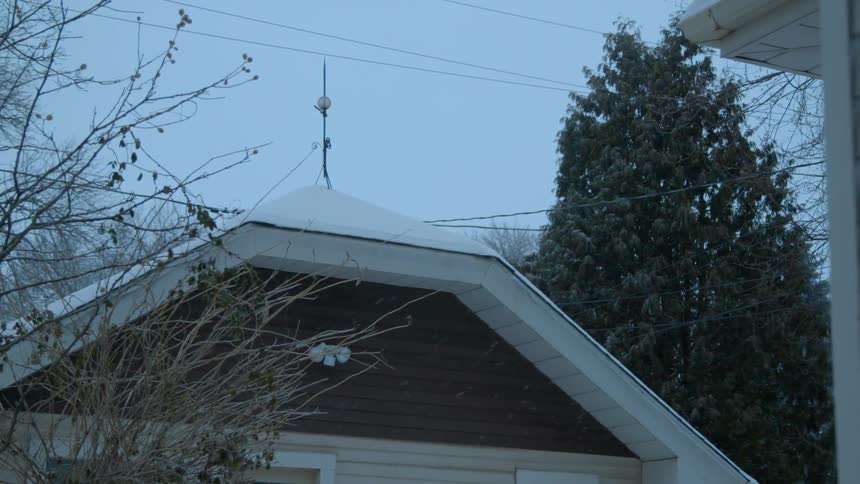 Snow falls onto rooftops outside