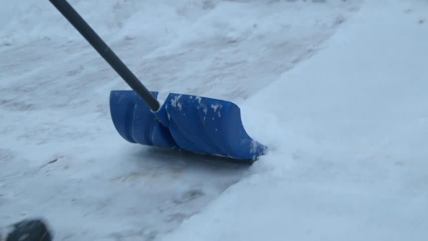A person shovels snow in a neighborhood