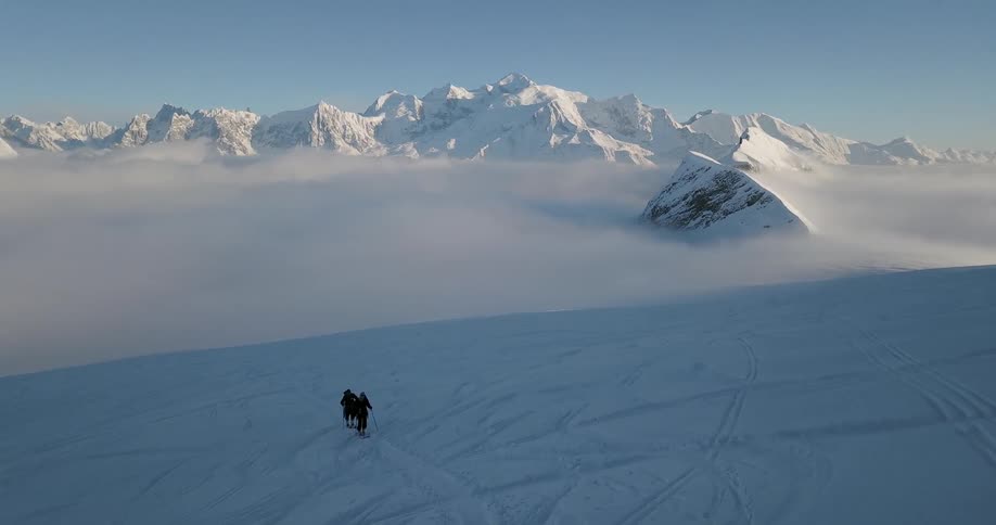 Two people walk across the snowy landscape