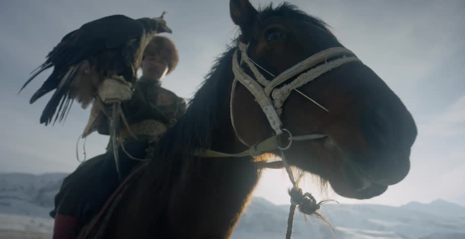 Man holds a large eagle as he sits on a horse