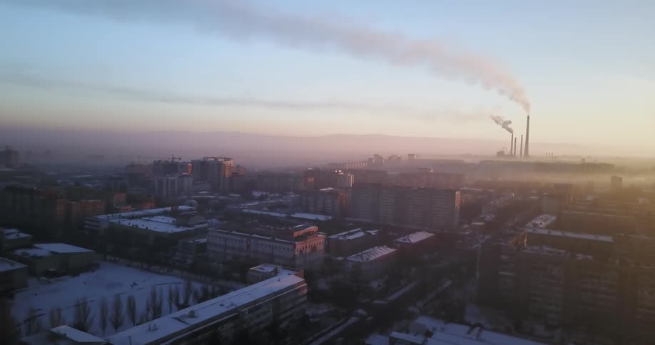 Smoke rises from a smokestack in a city